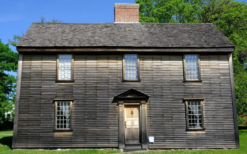 A New England "salt-box" style home with wooden siding and trim.