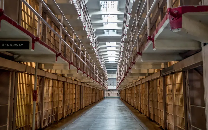 A corridor extends between two rows and three tiers of cells. Skylights let in light from overhead.