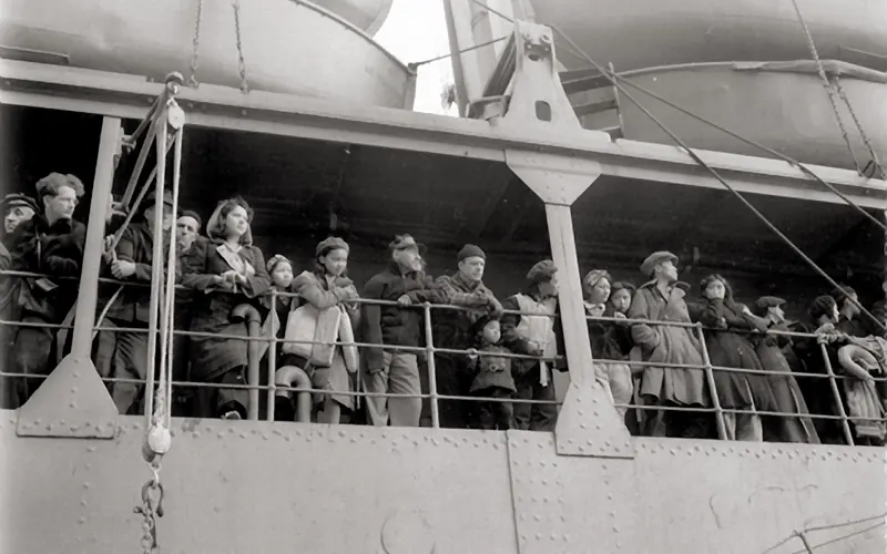 People crowd at the railing of a ship