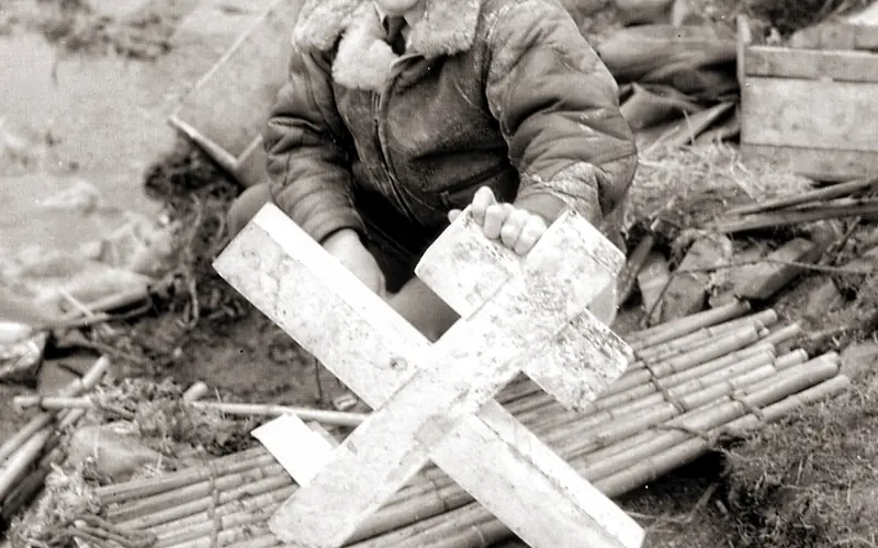A uniformed man holds up a broken Russian cross