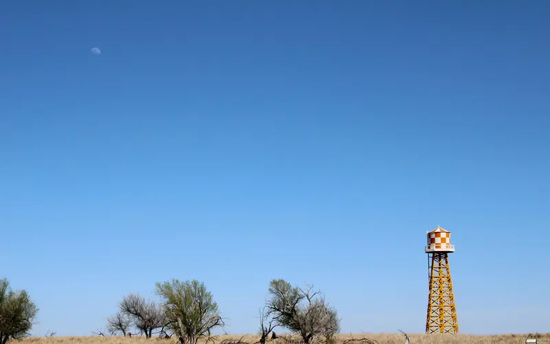 A water tower on the horizon next to trees