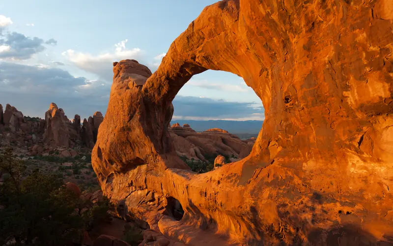 a broad, red arch with rock pinnacles in the background