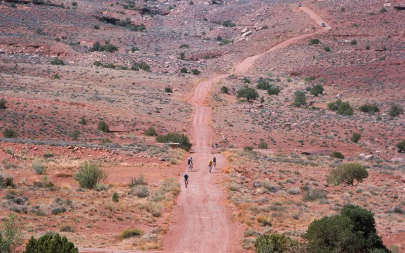 a long gravel road with cyclists on it