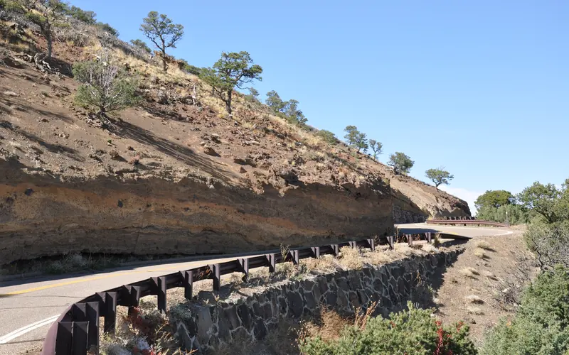 Layers of rock are visible in the steep hillside along a road.