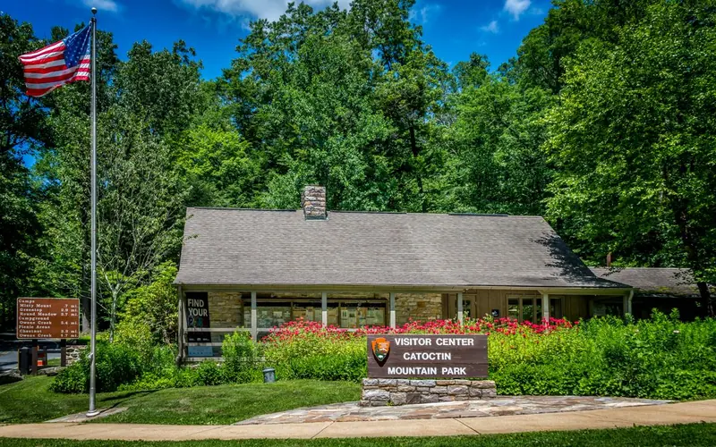 A stone and wood building with plants and flowers in front