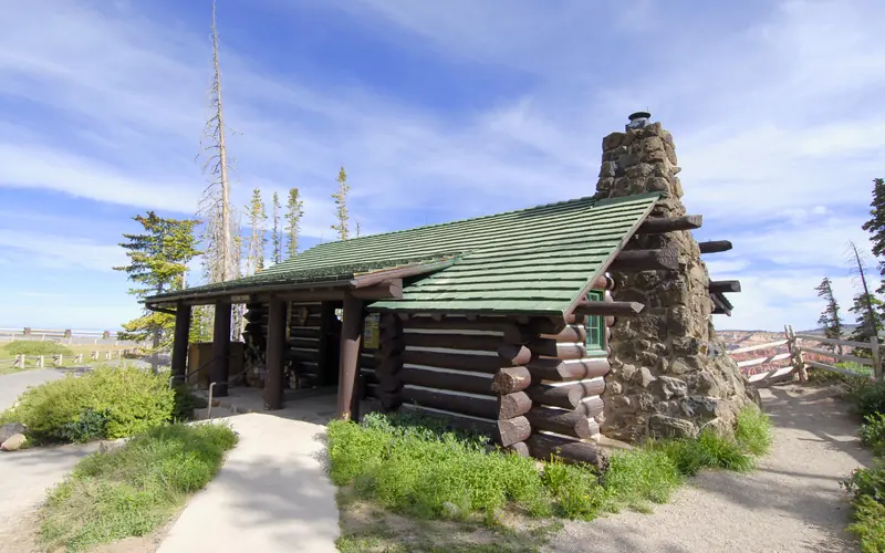 A small log cabin with a stone chimney on one side.
