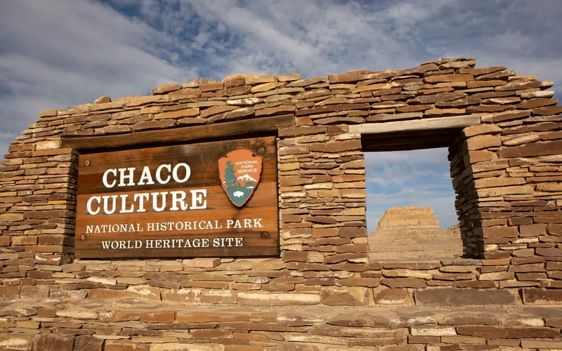 The entrance sign to Chaco Culture made out of sandstone and showing Fajada Butte through a window.