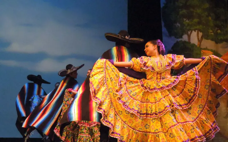 Women in swirling skirts and men with sombreros and colorful ponchos dance onstage