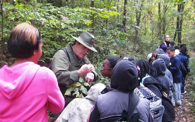 Park ranger showing a group of school children the critter on his arm.