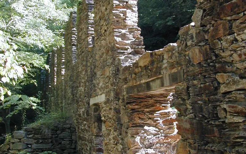 Stone ruins of the Marietta Paper Mill surrounded by lush green vegatation.