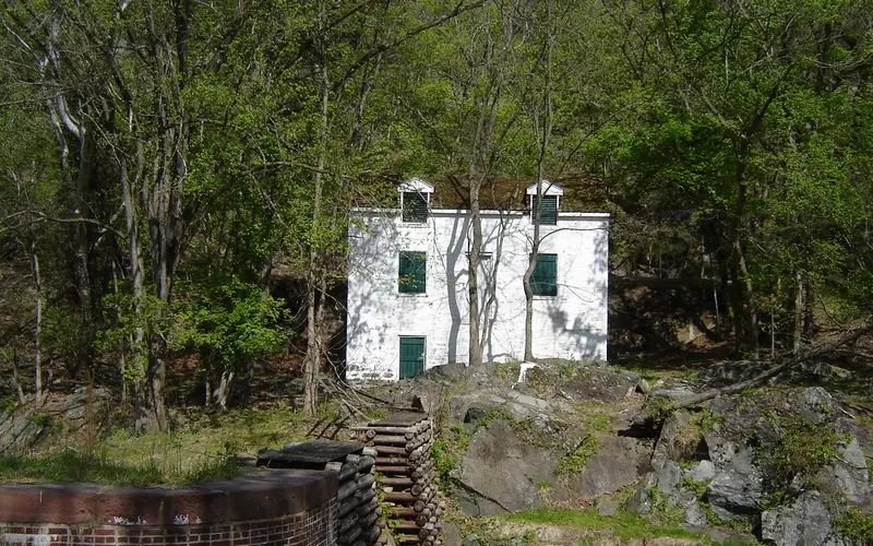 A whitewashed lockhouse sits above a stone lock with wooden crib.