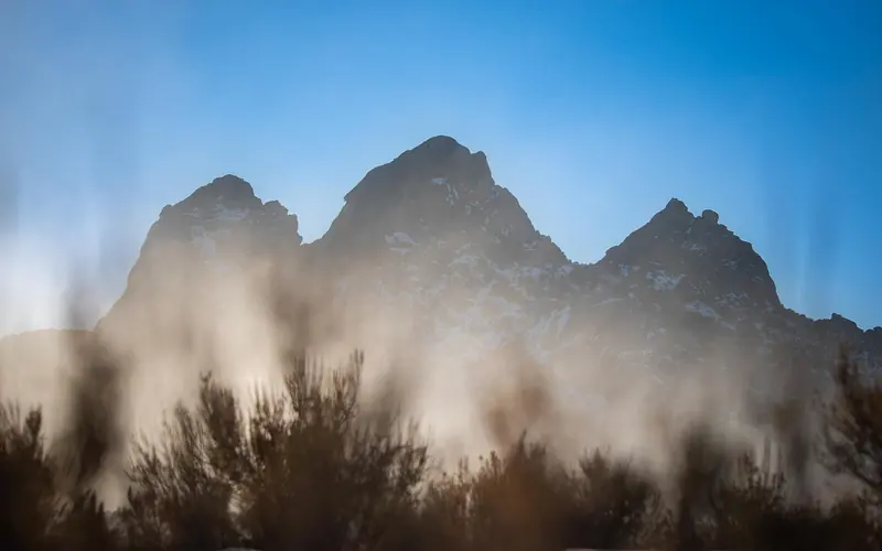 3 silhouetted foggy granite formations highlighted by golden sunlight.