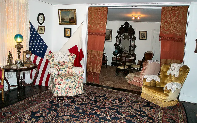 front parlor, two easy chairs, American Flag and Red Cross flag in corner behind one chair.