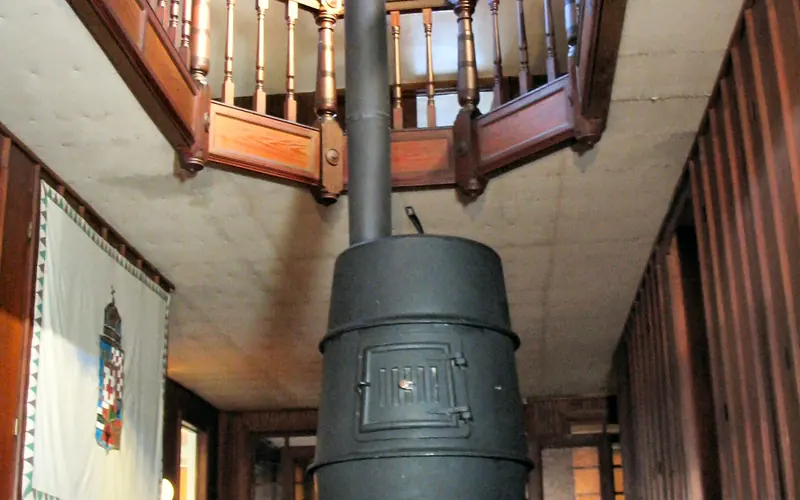 large potbelly stove in center hallway with open view to third floor