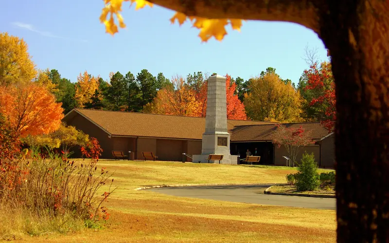 The Visitor Center and US Monument are framed by orange and yellow trees.
