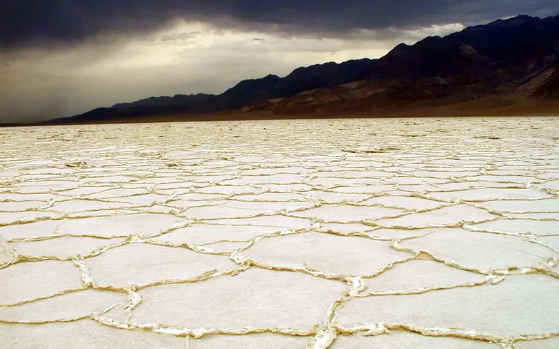 white salt flats with dark gray clouds