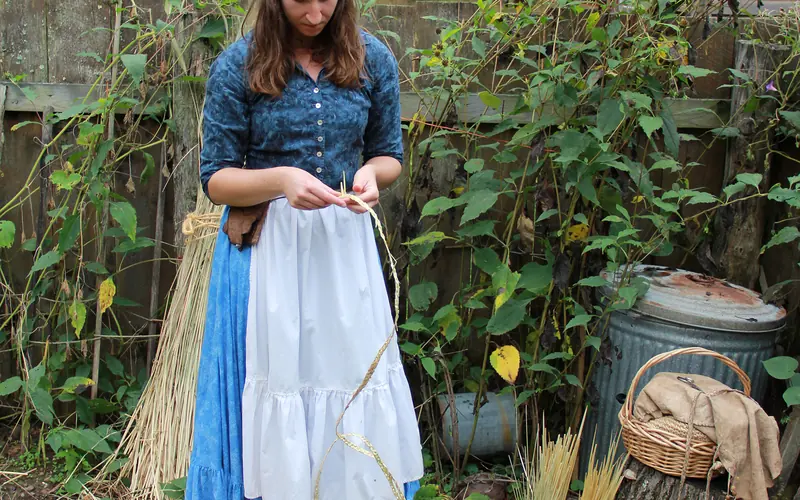 A woman braids rye straw for hatmaking