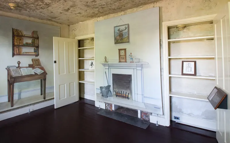 Color photo of the parlor in the Poe House showing illustrations of furniture on the walls.
