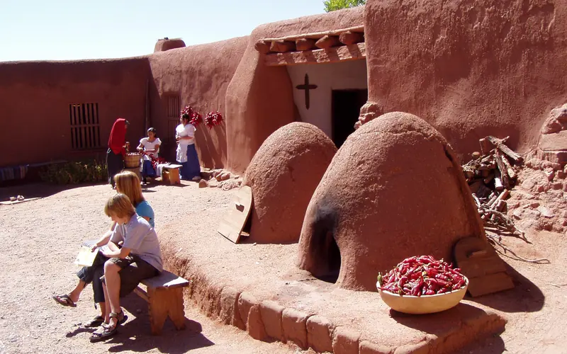 adobe buildings including two beehive-looking ovens with people in a courtyard