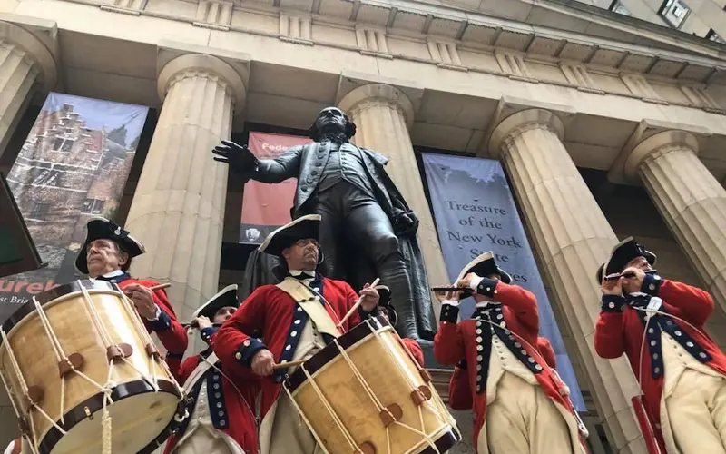 Five men dressed in Revolutionary War outfits play fife and drums