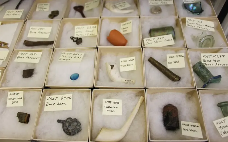 Small boxes in rows contain small artifacts, including broken pipes and glass bottles.