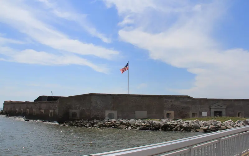 Fort Sumter with a US flag flying above the fort with dock in the foreground