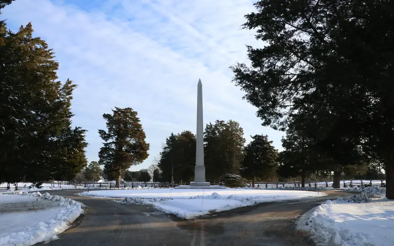 A large monument sits in the middle of a roundabout with snow on the ground