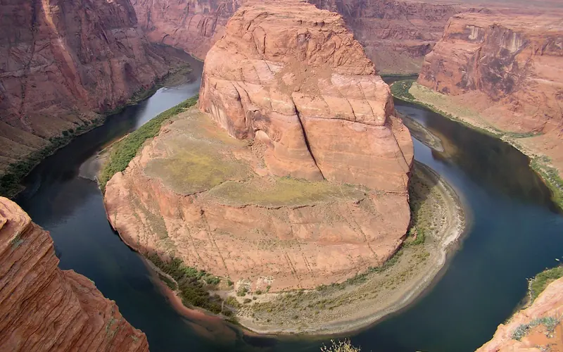 Green river winds through high cliffs.
