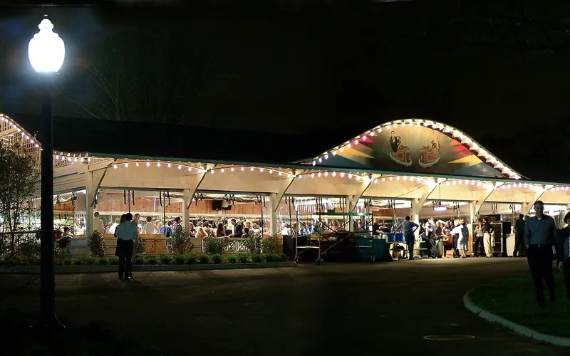 outdoor scene of open dance pavilion illuminated and evening dance crowd inside.