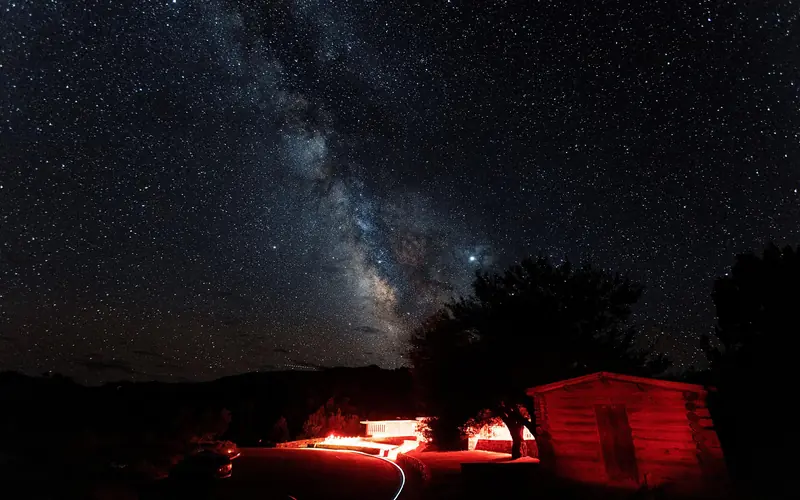 Colorful Milky Way over the red lit Lehman Caves Visitor Center