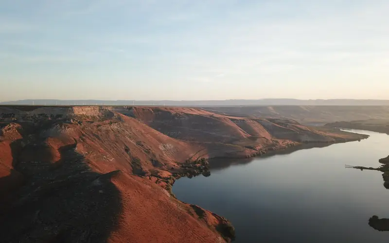 Steep, rocky bluffs line a river, awash in warm sunset colors