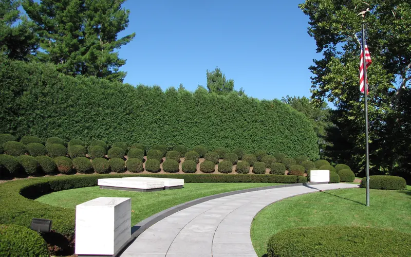 Two marble ledger stones each mark a grave in a semicircular landscaped plot with a flagpole.