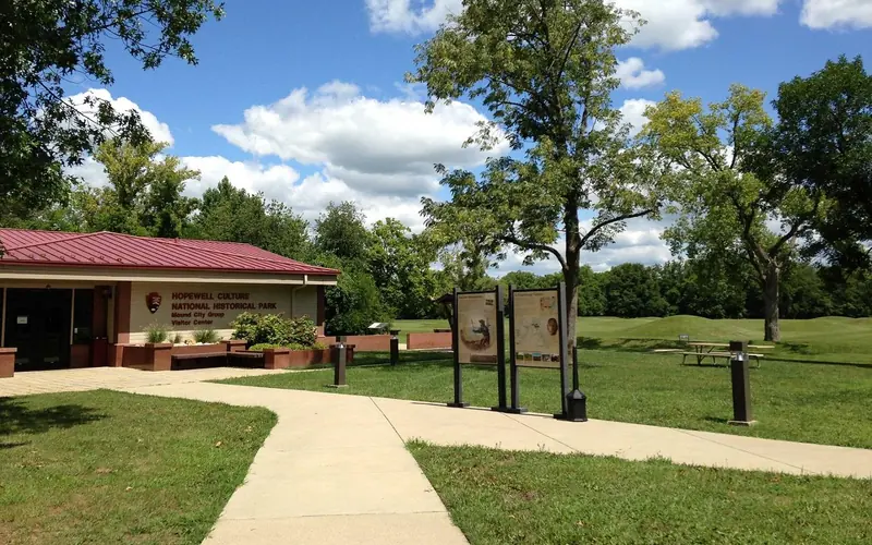 A tan building with a red-peaked roof surrounded by green grass and tan sidewalks
