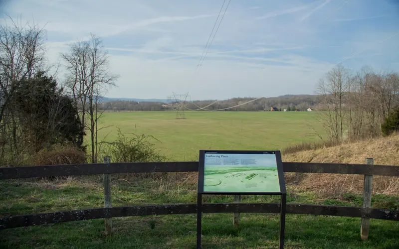 An overlook area showing a green grassy field with a panel showing artwork and text