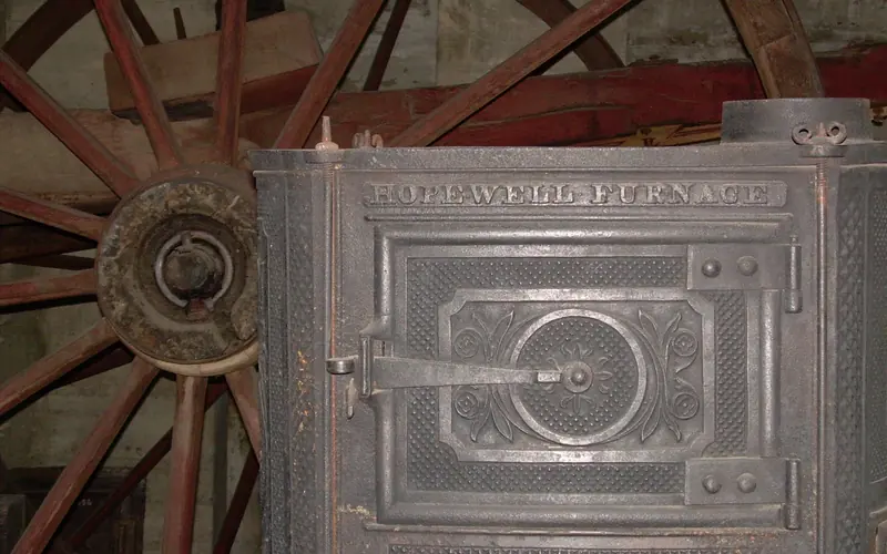 Side view of Hopewell Stove in front of wagon running gear.