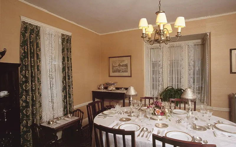 Dining room with oval dining table with six place settings of silver and fine china.