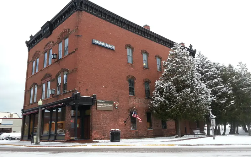 Three story brick building, with snow covered trees along the right side