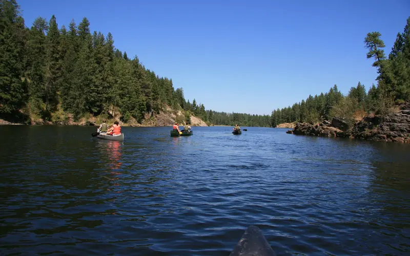 People canoeing down Lake Roosevelt on a day with blue skies.