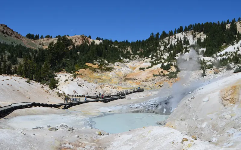 A boardwalk passes through a colorful, steaming hydrothermal basin.