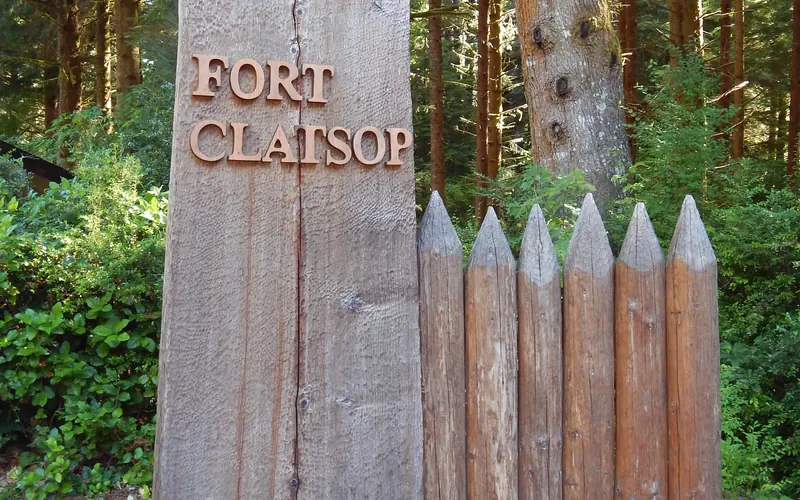 A wooden sign standing as a tall rectangle, the words Fort Clatsop carved of wood placed on it.