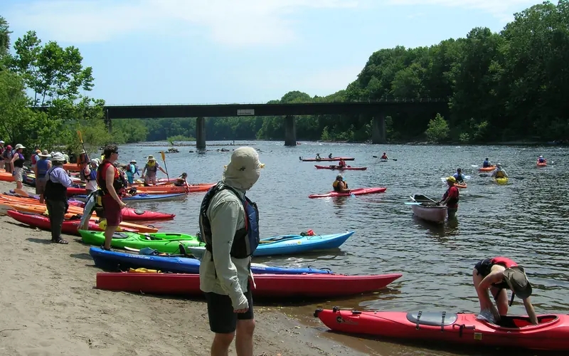 Kayakers enter the river from a riverside beach