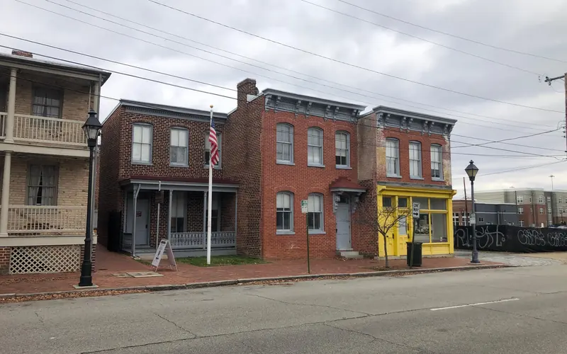 3 red brick, two-story buildings, with a US flag flying and an overcast sky