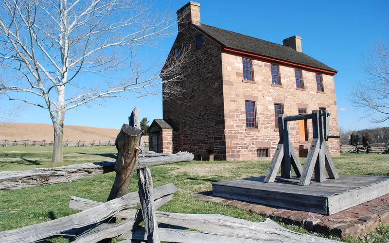 View of Stone House, with worm rail fence and well in front yard.