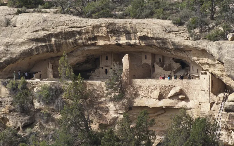 A cliff dwelling within a cliff alcove seen from across a canyon