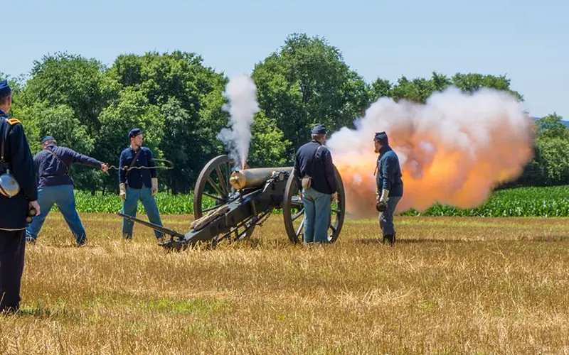Smoke and fire erupt from an artillery piece as it is fired by Union soldiers.