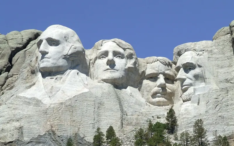 Closeup photo of Mount Rushmore under a bright blue sky.
