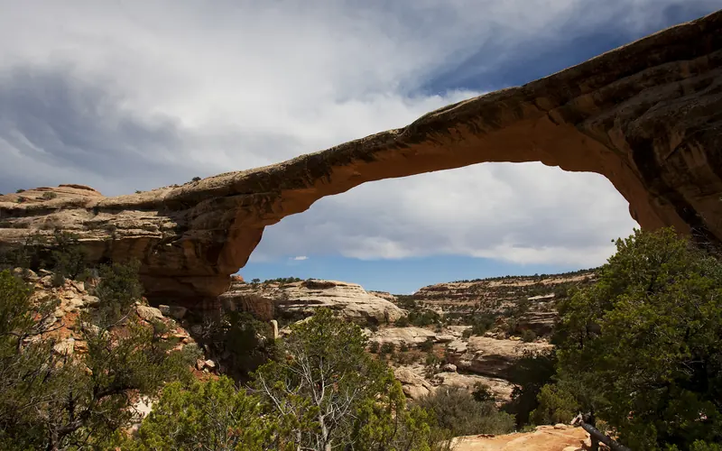 Sipapu Bridge with a blue sky and clouds overhead