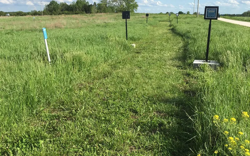A mowed path through prairie. There are numbered signs along the trail.
