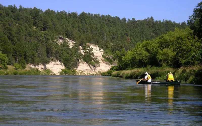 Two people in one canoe paddle along the bluffs of the Niobrara NSR.