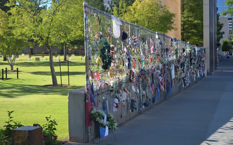 Fencing with pictures, stuffed animals and other tokens left on it.